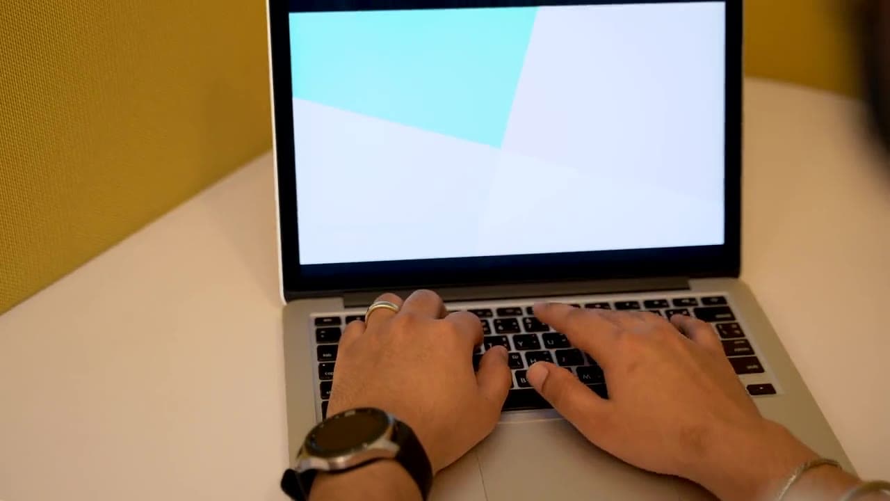 A builder typing on a laptop at a sunlit desk